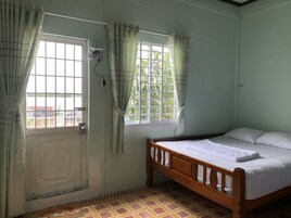 Una habitación con cama, ventana con cortinas, puerta y suelo de baldosas.