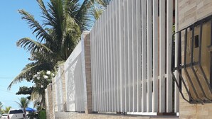 Acerado al lado de un edificio con pared de ladrillo y cerca blanca.