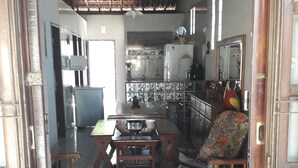 Un interior tradicional con suelo de baldosas, muebles de madera y una zona de cocina con refrigerador y armarios.