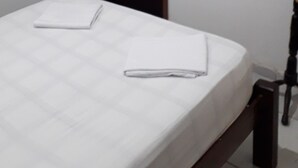 Un dormitorio con cama, televisión montada en la pared y una puerta.