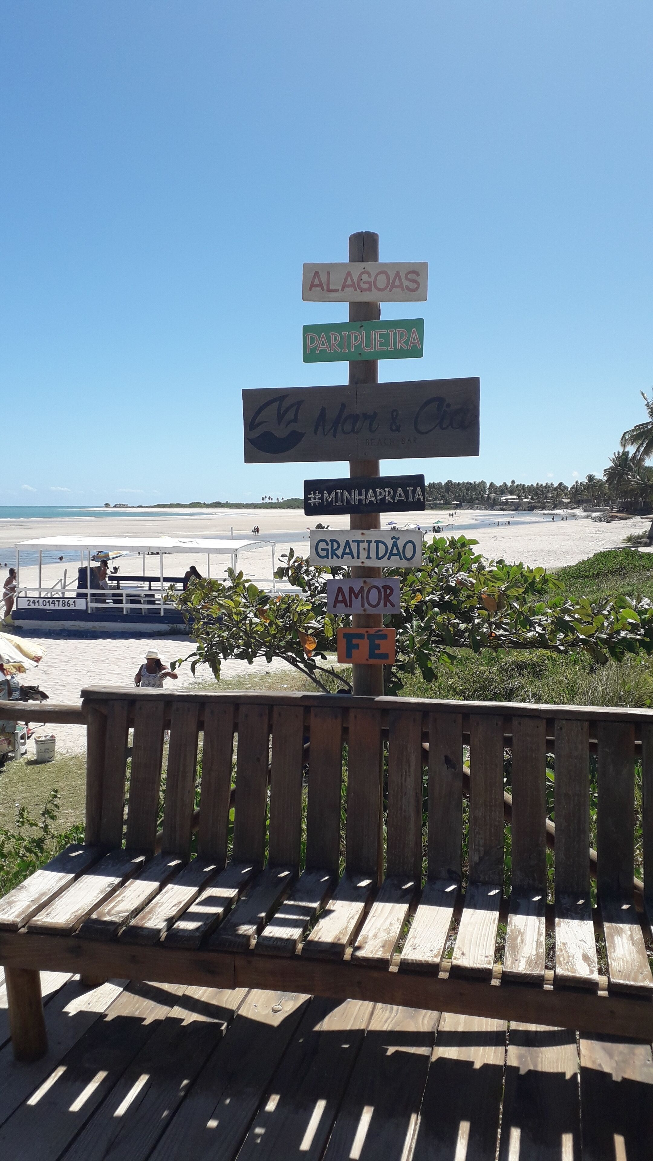 A wooden bench with a signpost in the background.