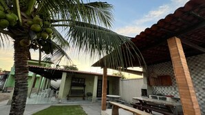 Un patio con mesa y bancos de madera, un pequeño jardín con una palmera y una cocina con salpicadero de azulejos.
