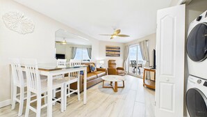 A modern living room with a dining area, a sofa, a coffee table, and a ceiling fan. - Coastal Elegance Upscale Renovations Ultimate Vacation Experience Surf Beach 505 (Treasure Island)