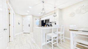 A modern kitchen with white cabinetry, a central island, and pendant lighting. - Coastal Elegance Upscale Renovations Ultimate Vacation Experience Surf Beach 505 (Treasure Island)
