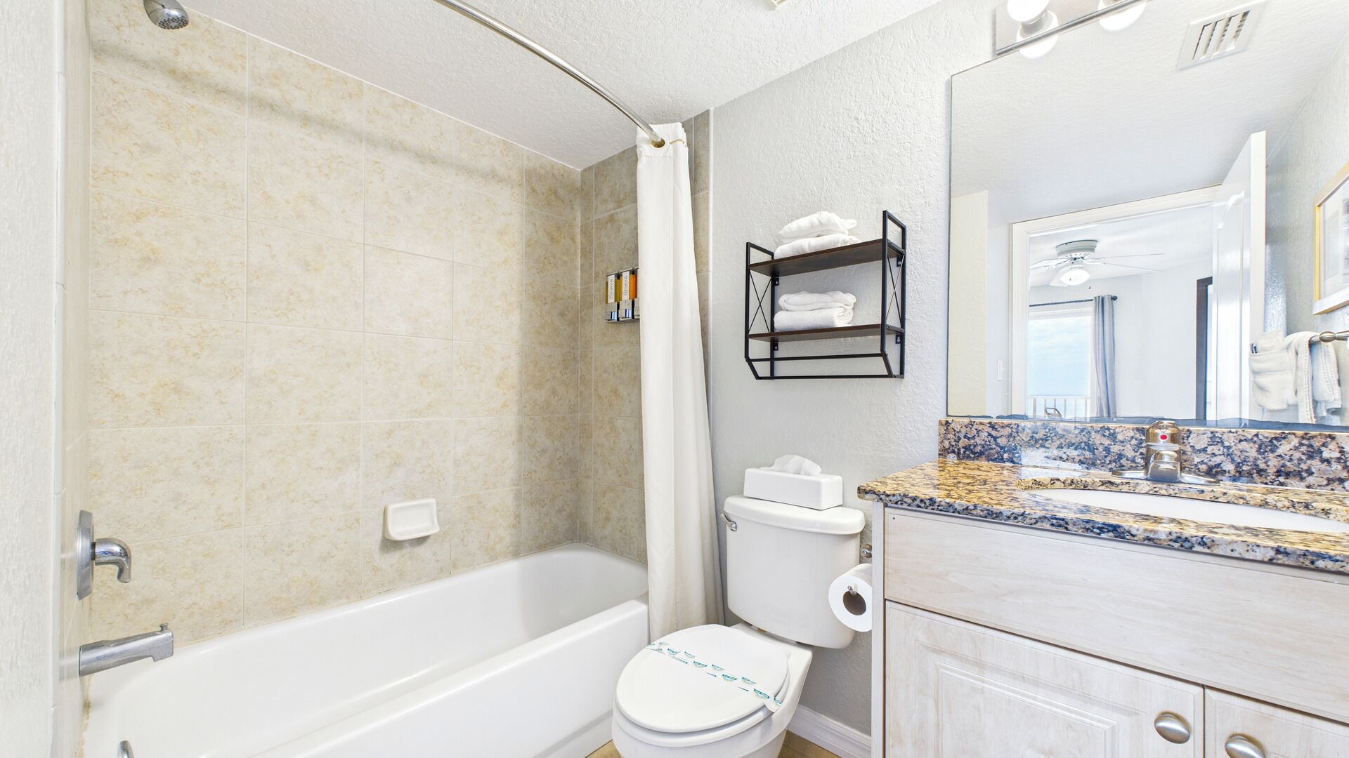A bathroom with a bathtub, toilet, and a vanity with a mirror.