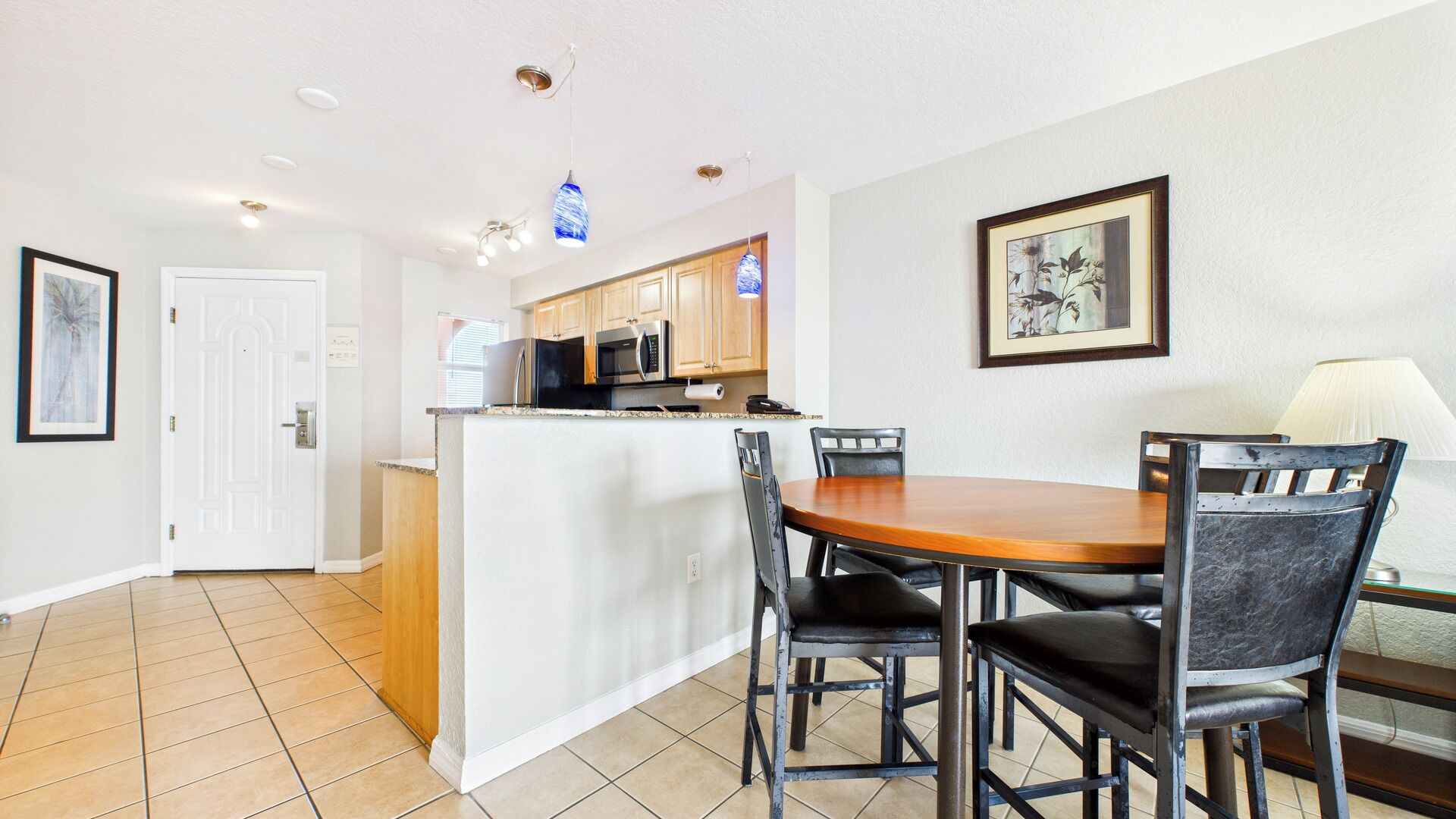A compact kitchen with a central island, wooden cabinets, and a dining area with a table and chairs.