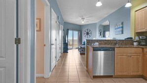 A kitchen with a stainless steel dishwasher, wooden cabinets, and a granite countertop. - Surf Beach 604 - Spectacular Sunsets - Beach Front (Treasure Island)