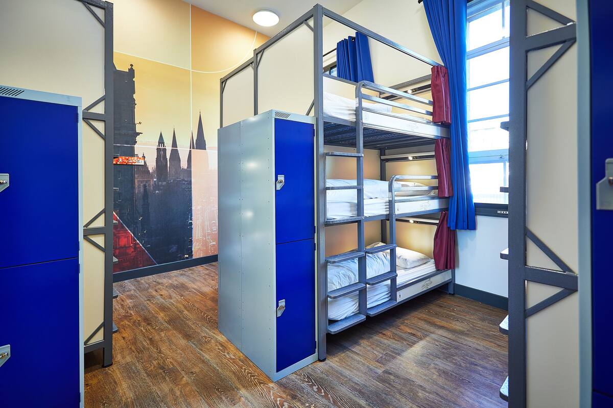 Dormitorio con literas, un armario y un mural con vista a la ciudad.