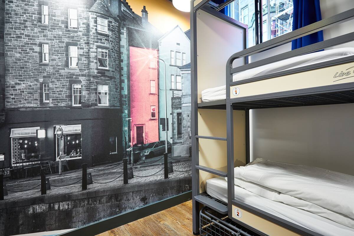 Una cama litera con colchón y un mural en la pared que representa una calle de la ciudad.