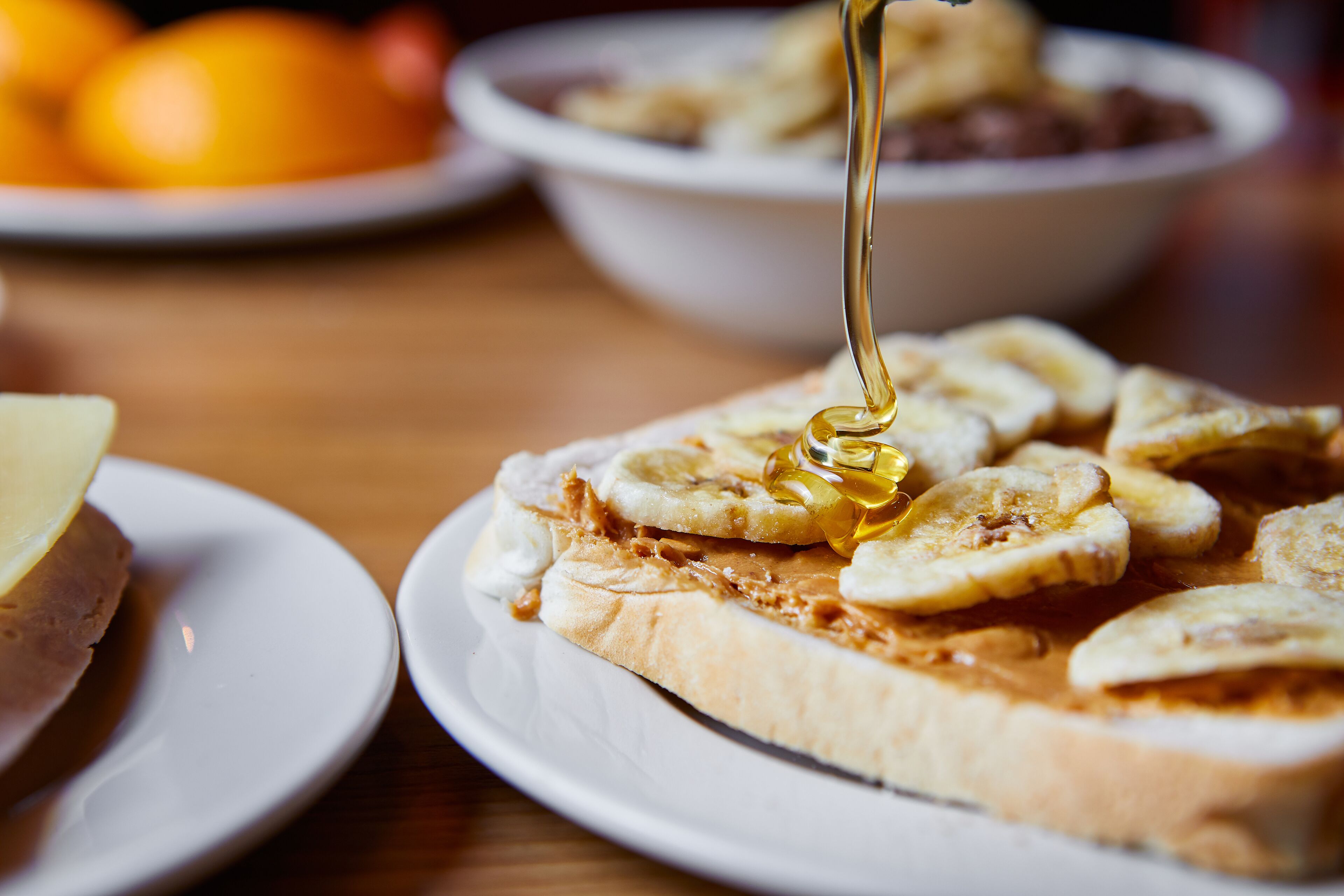 A sandwich with peanut butter and banana slices on a white plate.