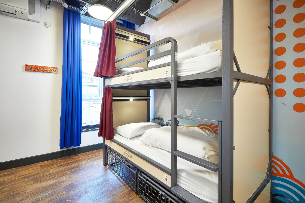 Habitación con literas, una ventana, cortinas y un adorno en la pared.