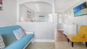 Ein modernes Wohnzimmer mit einem blauen Sofa, einem gelben Sessel und einer Küchenzeile mit einer Fisch-Dekoration.