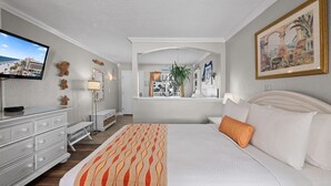 A hotel room with a bed, a dresser, a television, a window with a view, and a painting on the wall.