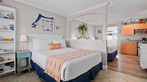 A bedroom with a bed, bedside table, lamp, and a wall decoration.