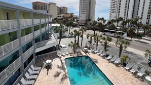 A hotel with a pool, multiple floors, and a view of surrounding buildings.