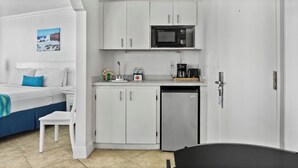 A compact hotel room with a bed, a small kitchenette, and a bathroom. - Pelican Pointe 417:Walk to Beach~Pool~Free Parking (Clearwater Beach)