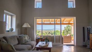 Un salón amplio con un gran ventanal corredera que da a un patio exterior.
