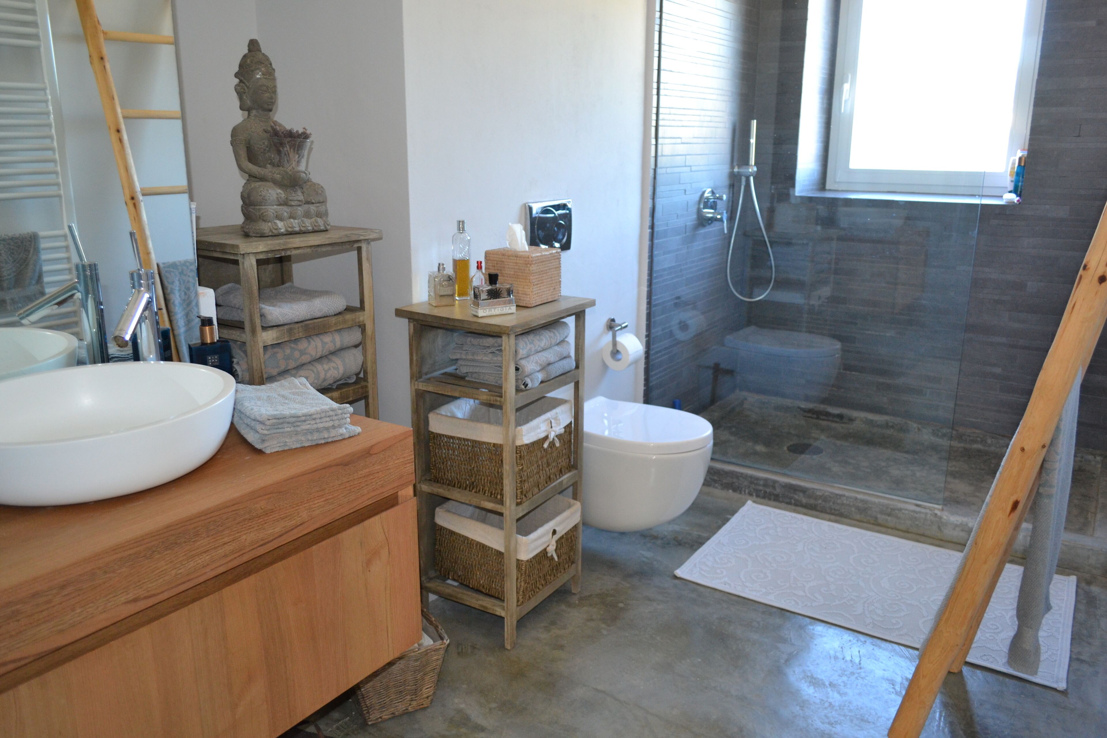 Un baño con tocador de madera, un lavabo blanco grande, un inodoro y una zona de ducha.