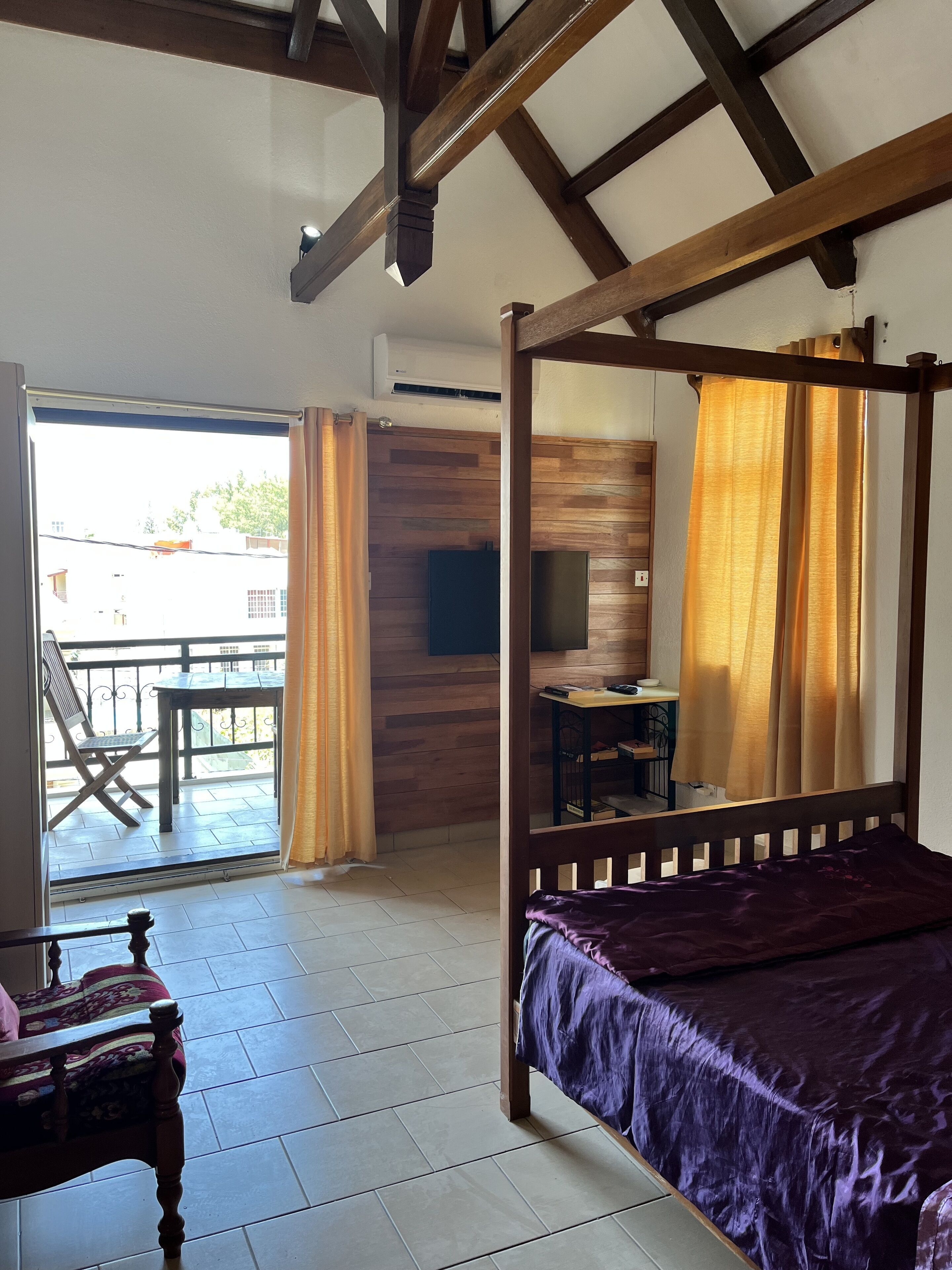 Una habitación con cama con dosel, una mesita con una silla y un balcón con mesa y sillas.