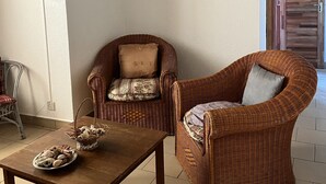 Ein Zimmer mit einem Holztisch, zwei Korbstühlen und einer Auswahl an Gebäck.