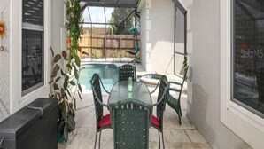 A covered patio area with a pool, outdoor furniture, and a ceiling fan.