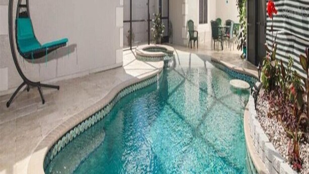A swimming pool with a glass ceiling, a crescent-shaped lounge chair, and a small garden area with plants.