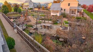 Un barrio residencial con casas, un jardín con terraza de madera y un sendero de piedra.