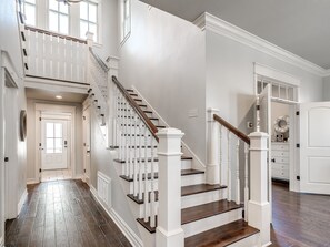 A grand staircase with white balusters and dark wood steps leading to a second floor.