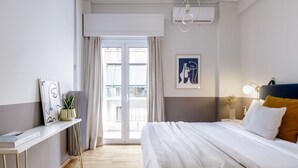 A modern hotel room with a large bed, a bedside table with a lamp, a window with curtains, and a view of the outside.