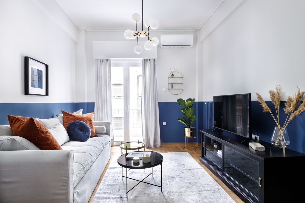 Ein modernes Wohnzimmer mit Sofa, Couchtisch, Fernseher und Zimmerpflanzen.