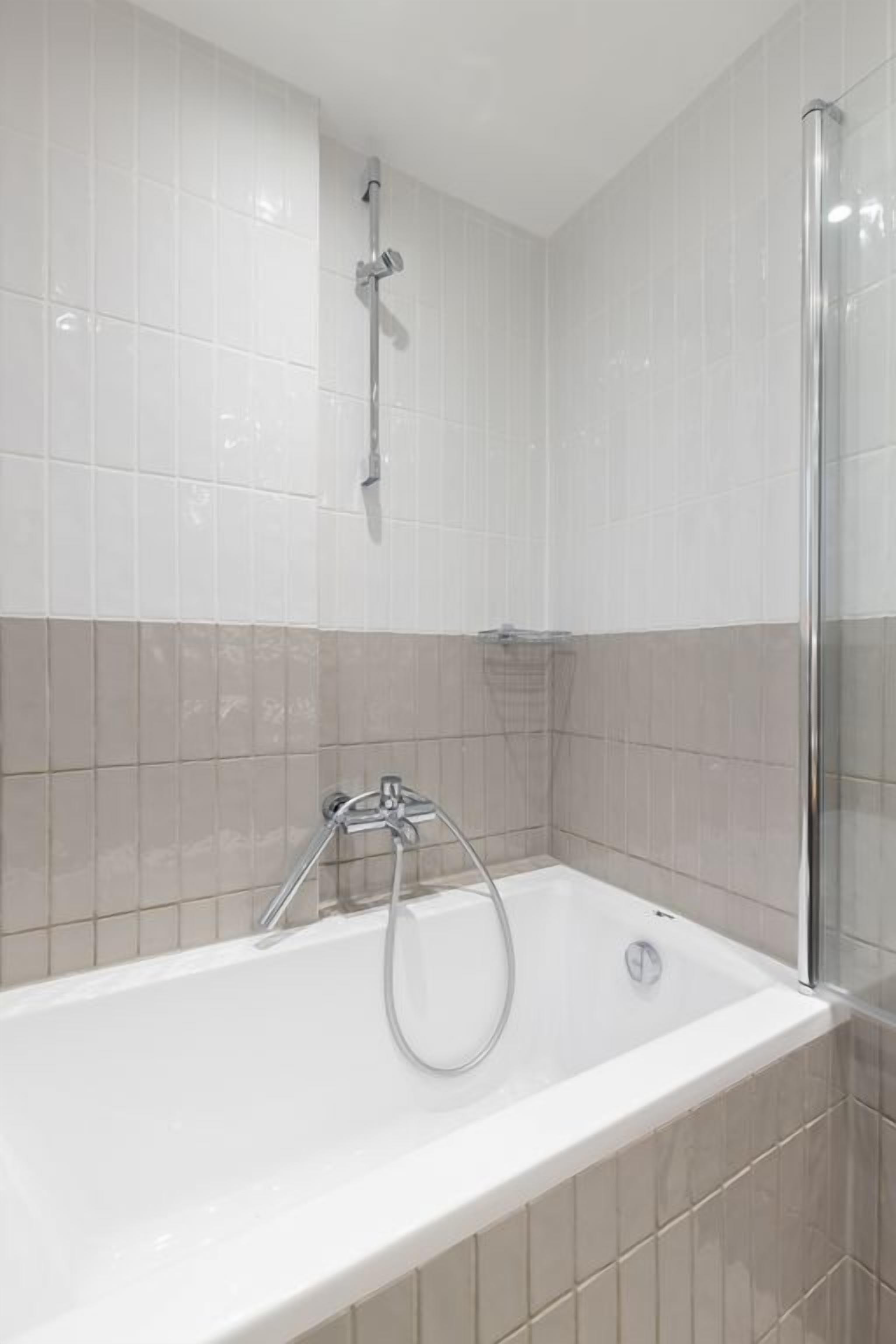 Une salle de bain moderne équipée d’une baignoire, d’une douche et d’un espace de douche séparé par des parois en verre.