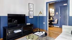 A modern living room with a flat-screen TV, black entertainment unit, and a round glass table.