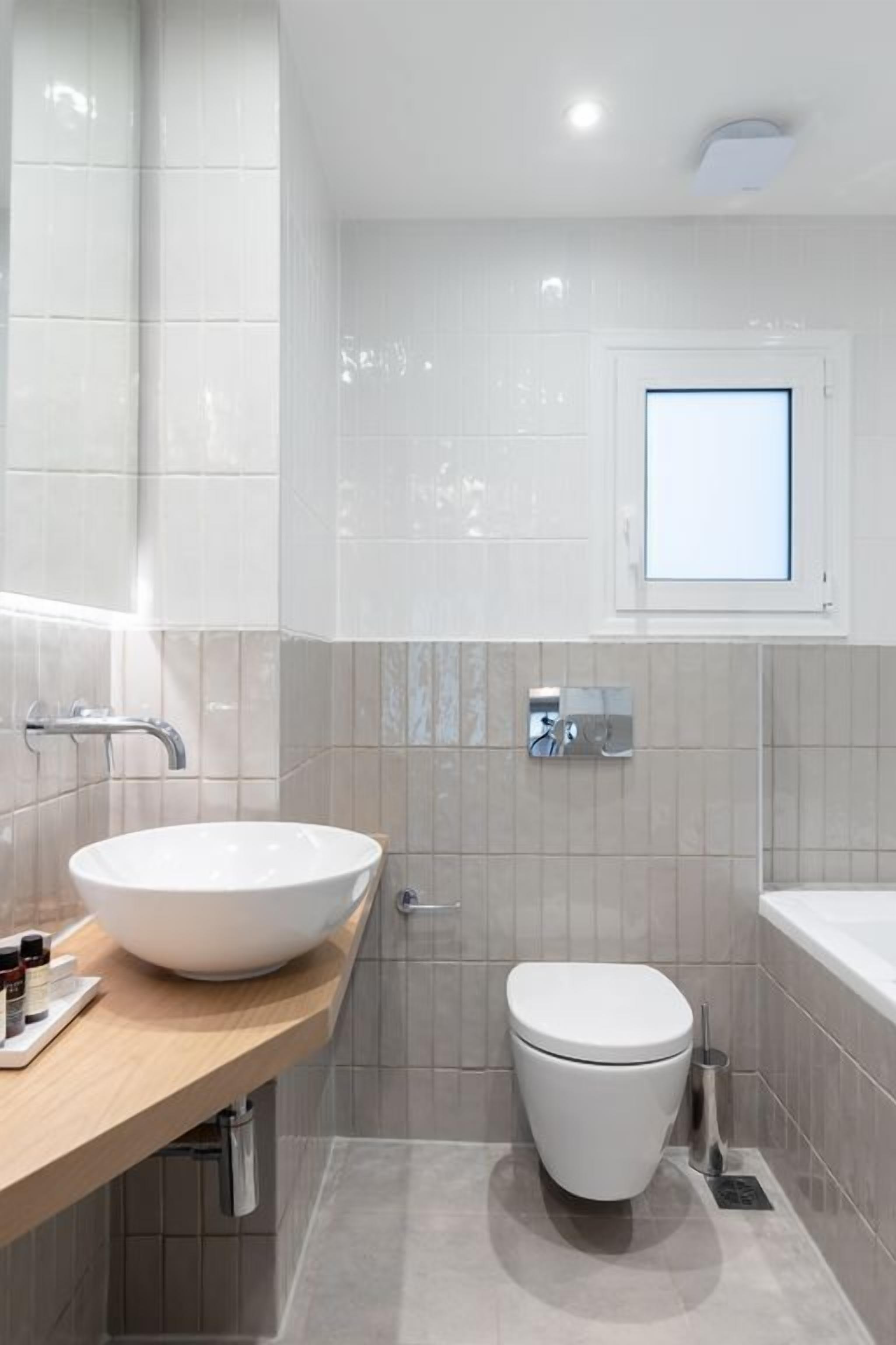 Un baño moderno con lavamanos, inodoro y bañera blancos.