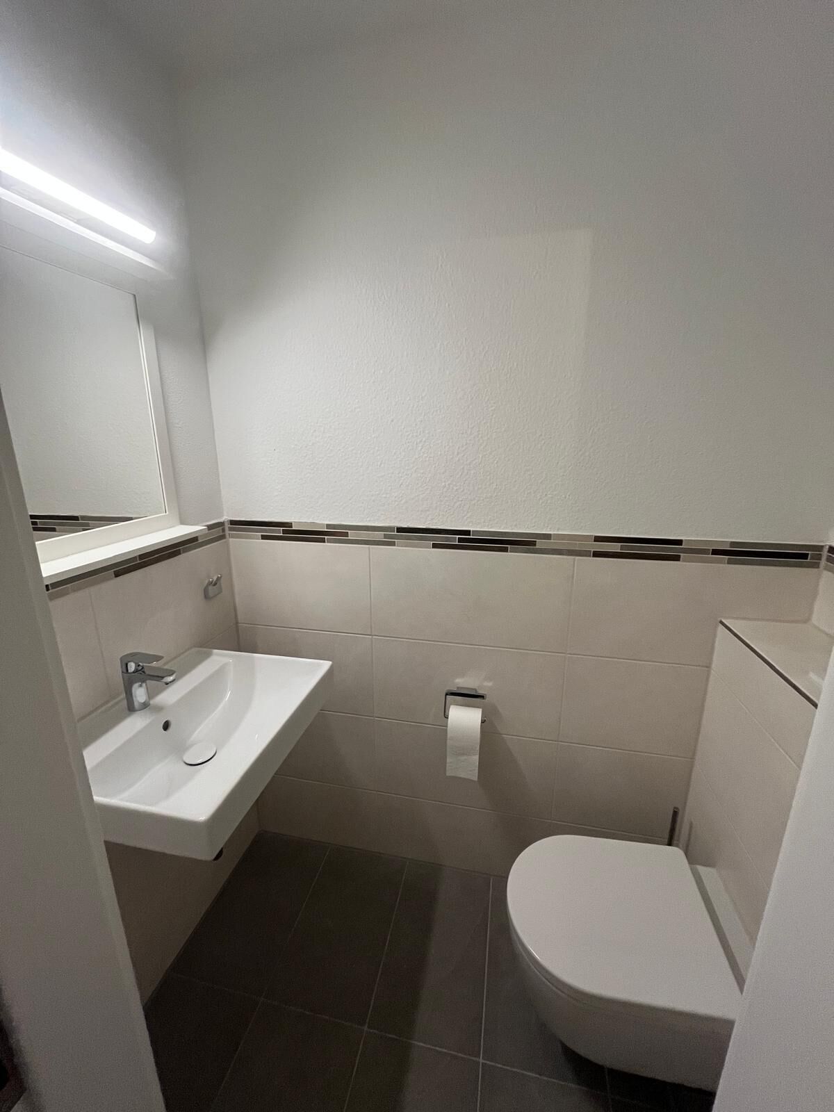 Ein Badezimmer mit einem weißen Waschbecken, einer Toilette und einem Spiegel.
