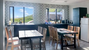 A kitchen with a dining area, large windows, and a view of a green landscape.