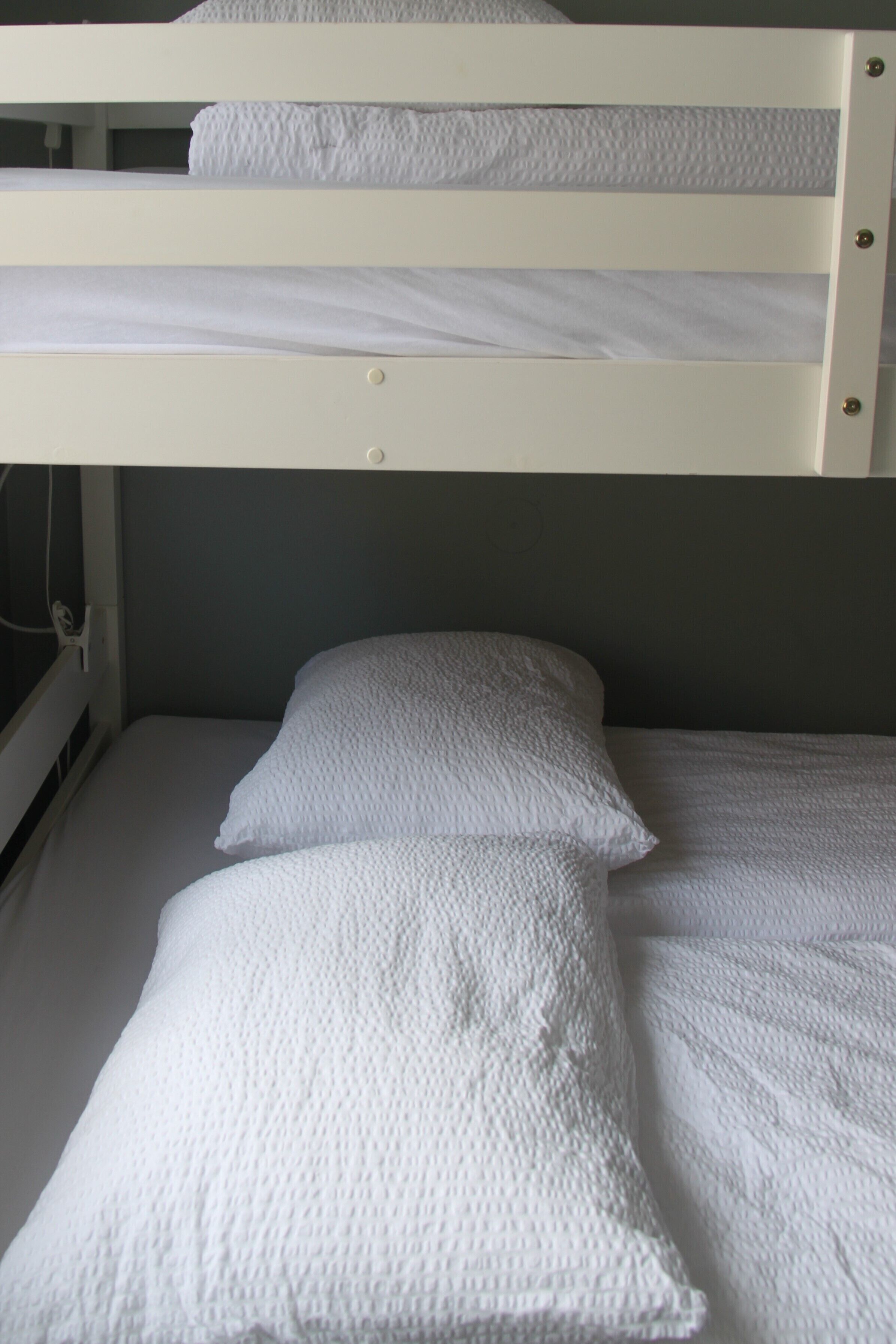 A bunk bed with white bedding and a headboard.