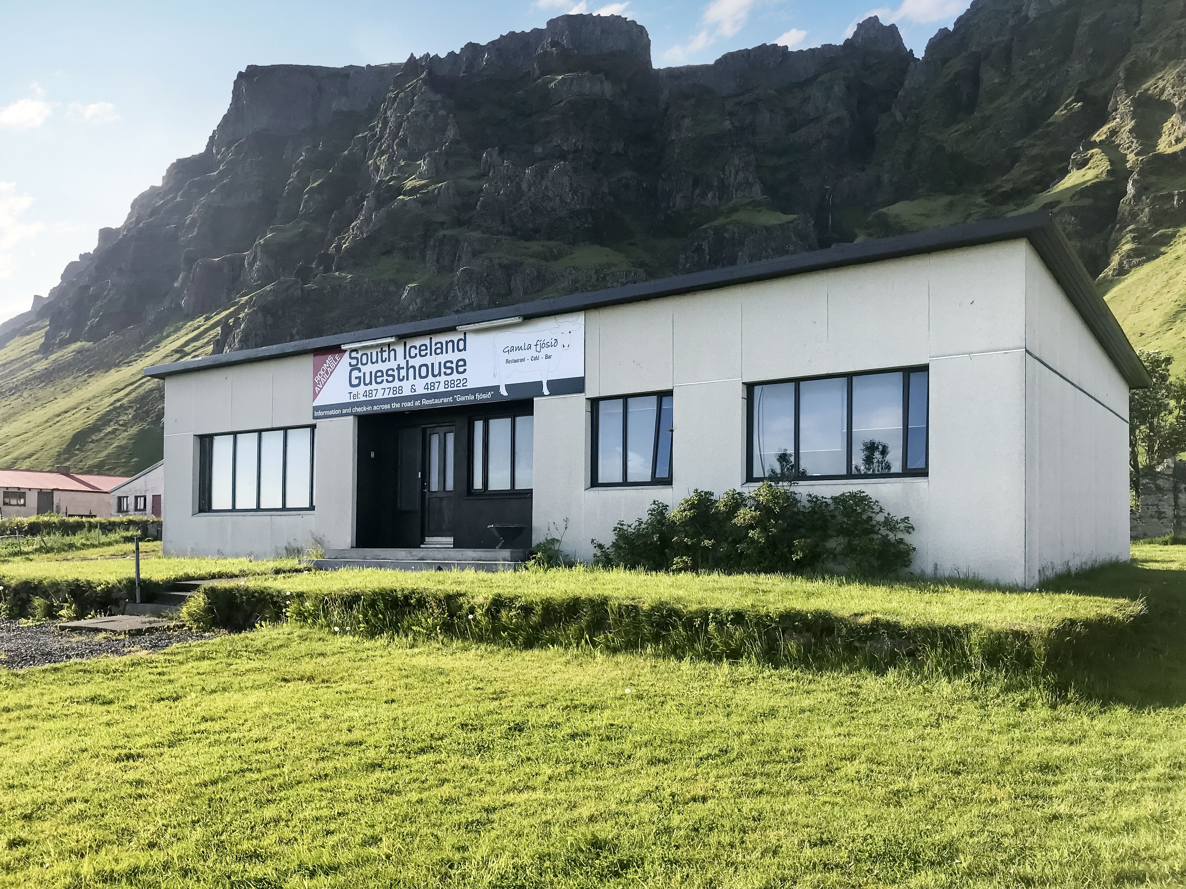 Een modern gebouw met de naam 'South Iceland Guesthouse' en een naambord.