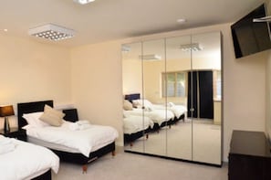 A hotel room with two beds, a large mirror, a TV, and a ceiling light fixture. - Cotswolds Valleys Accommodation-Stony Hs (Stroud)