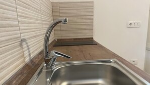 Eine moderne Küche mit Spüle aus Edelstahl, Holzarbeitsplatte und einer gefliesten Rückwand.