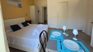 Ein Hotelzimmer mit einem Bett, einem Tisch für zwei Personen und einer Tür zu einem weiteren Raum.