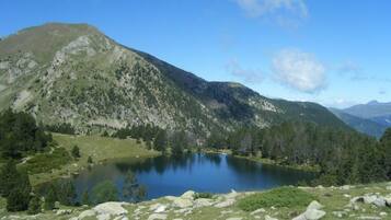 A mountainous landscape with a lake surrounded by greenery and rocks.