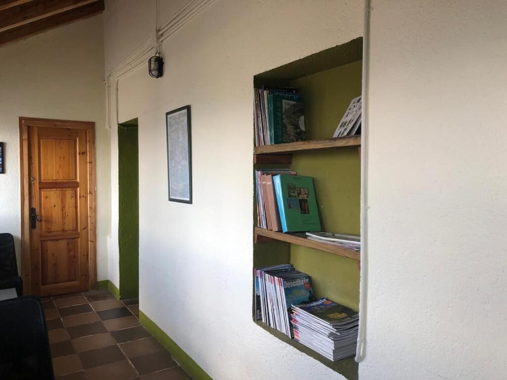 A hallway with a wooden door, a framed picture, and a bookshelf with books.