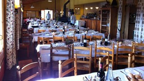 A restaurant with multiple tables set for dining, wooden chairs, and hanging pendant lights. - Refugi Cap del Rec - Hostel (Lles)