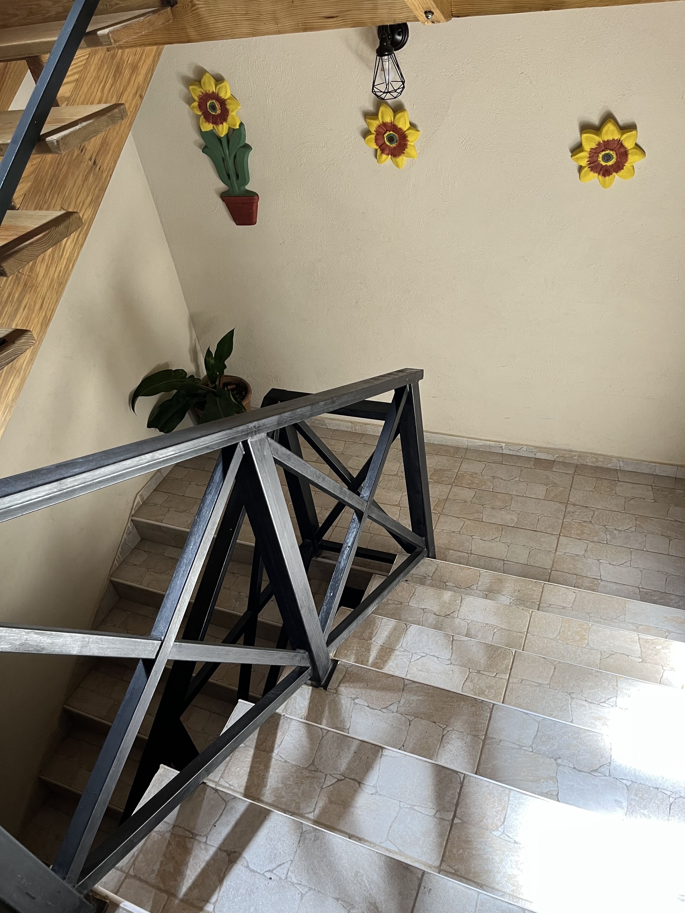 Eine Treppe mit Metallgeländer, einem Blumentopf und an der Wand befestigten Sonnenblumen.