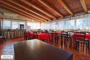 A restaurant with wooden beams, red tablecloths, and tiled flooring. - Casale del Vento (Aprilia)