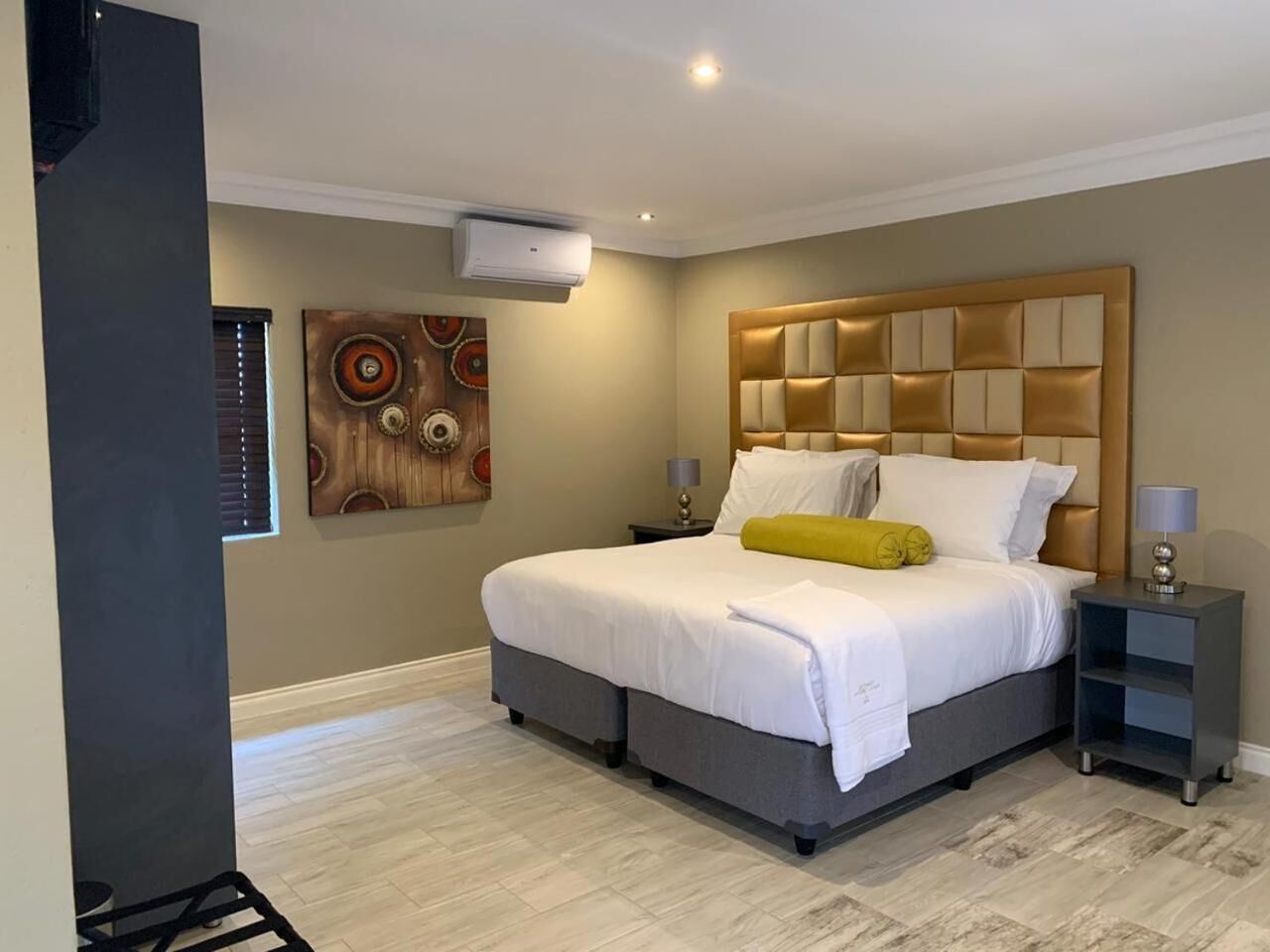 Een moderne slaapkamer met een groot bed, een hoofdbord met een geometrisch patroon en een wandairconditioning.