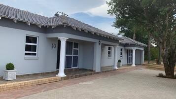 A two-story building with a tiled roof, numbered 10 and 9, featuring a covered walkway and a landscaped driveway.