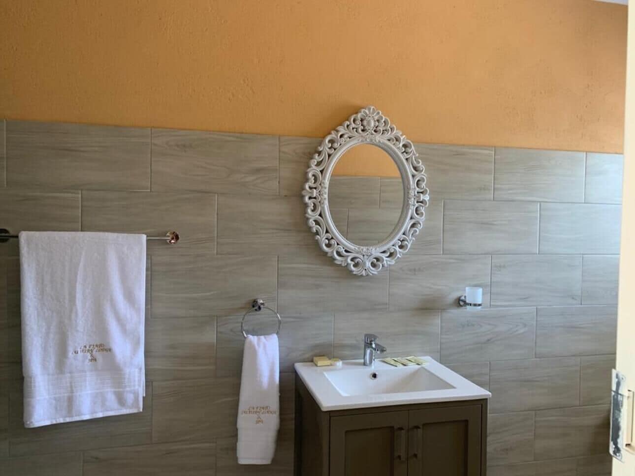 Une salle de bain avec un mur en bois, un lavabo blanc, un miroir et deux serviettes.
