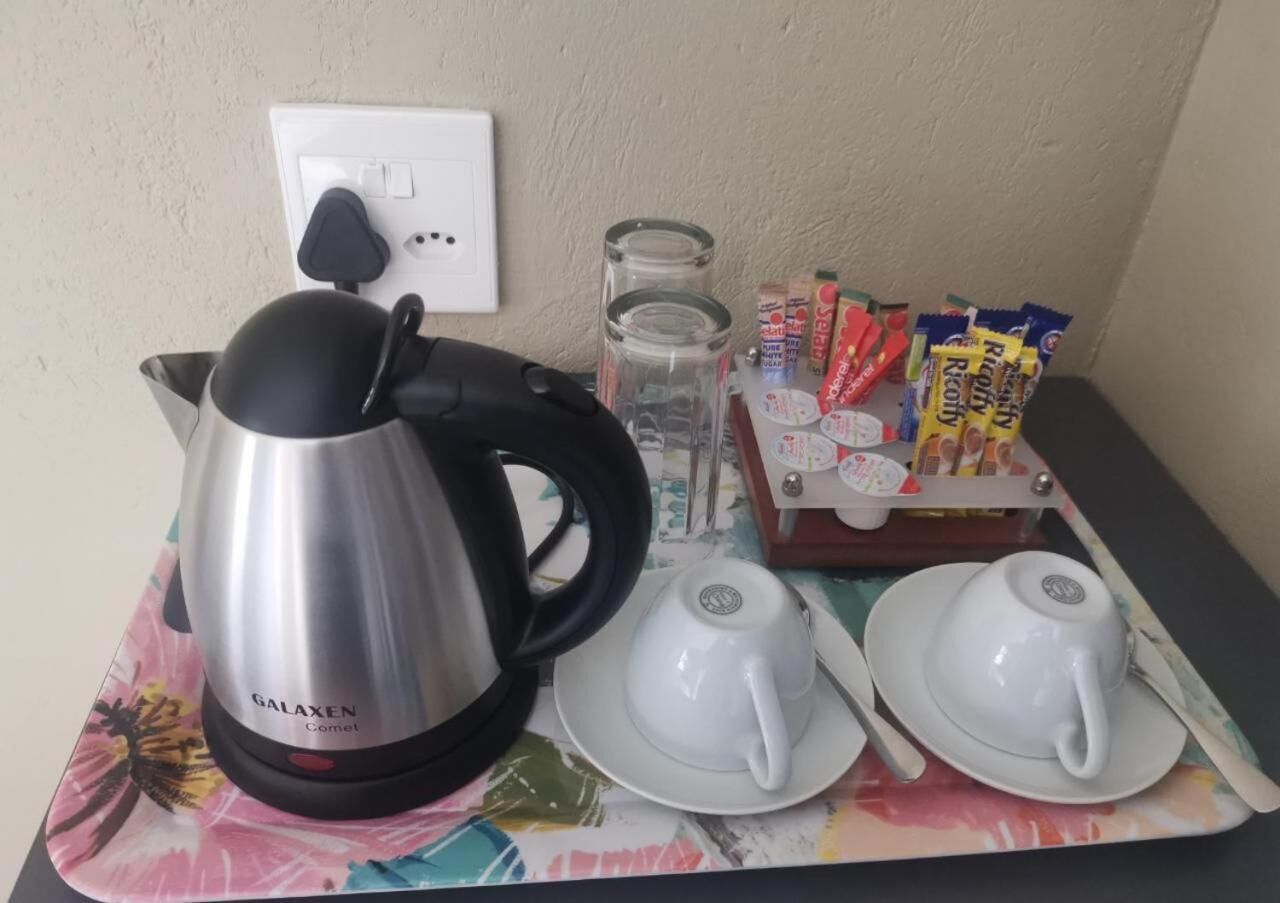 A table with a Galaxen coffee maker, two white cups, a glass jar, and a box of Rofly mints.