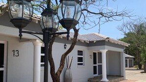 A building with a white facade, numbered doors, and a covered entrance area. - La Fiato Luxury Lodge (Polokwane)